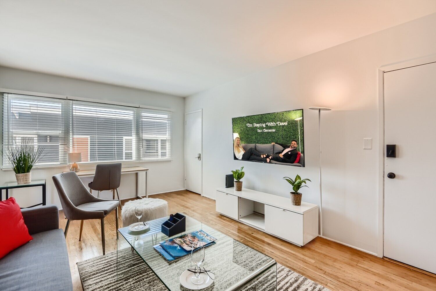 A modern living room with a sofa, chairs, a coffee table, and a TV mounted on the wall.
