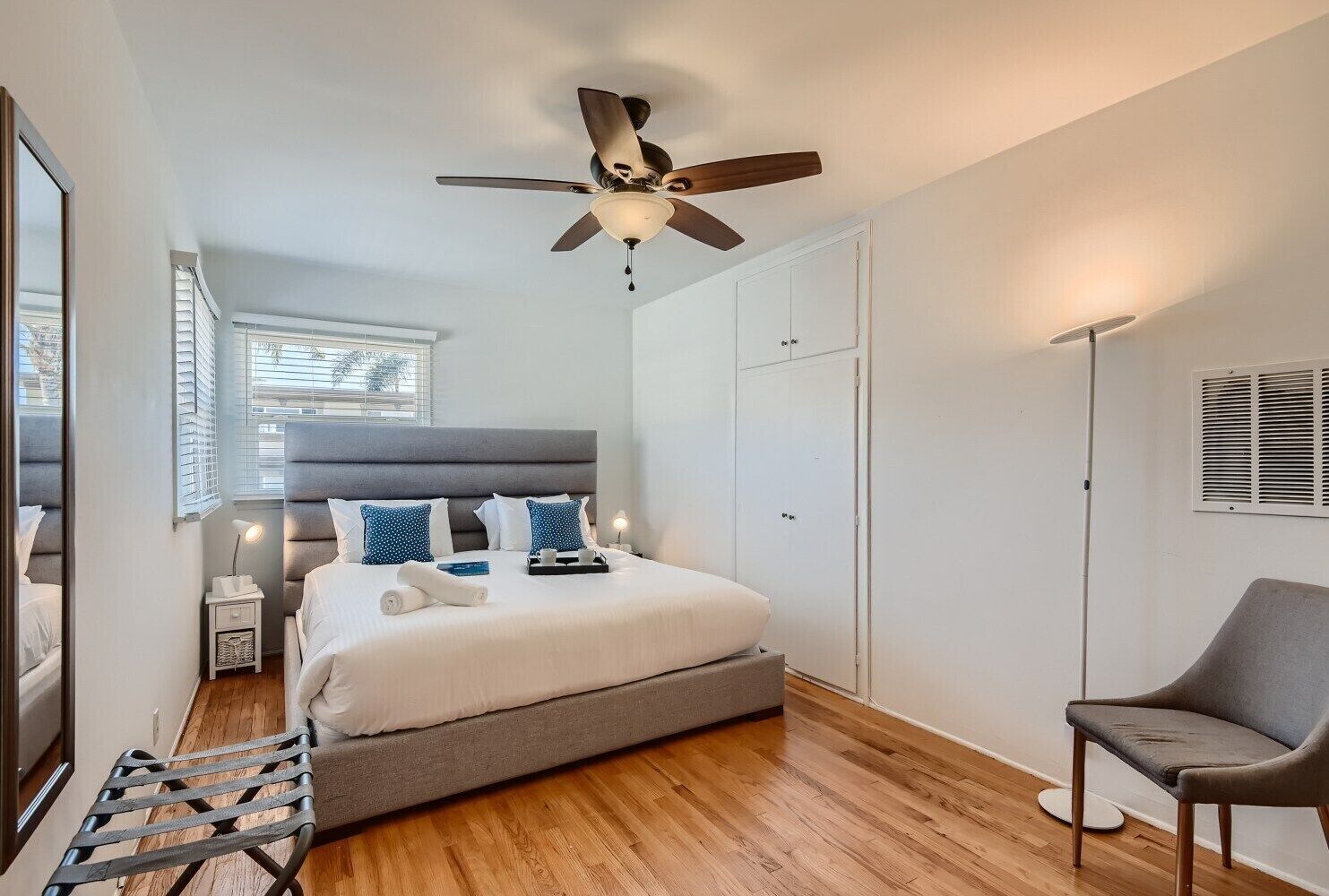 A bedroom with a bed, a ceiling fan, a chair, and a wardrobe.
