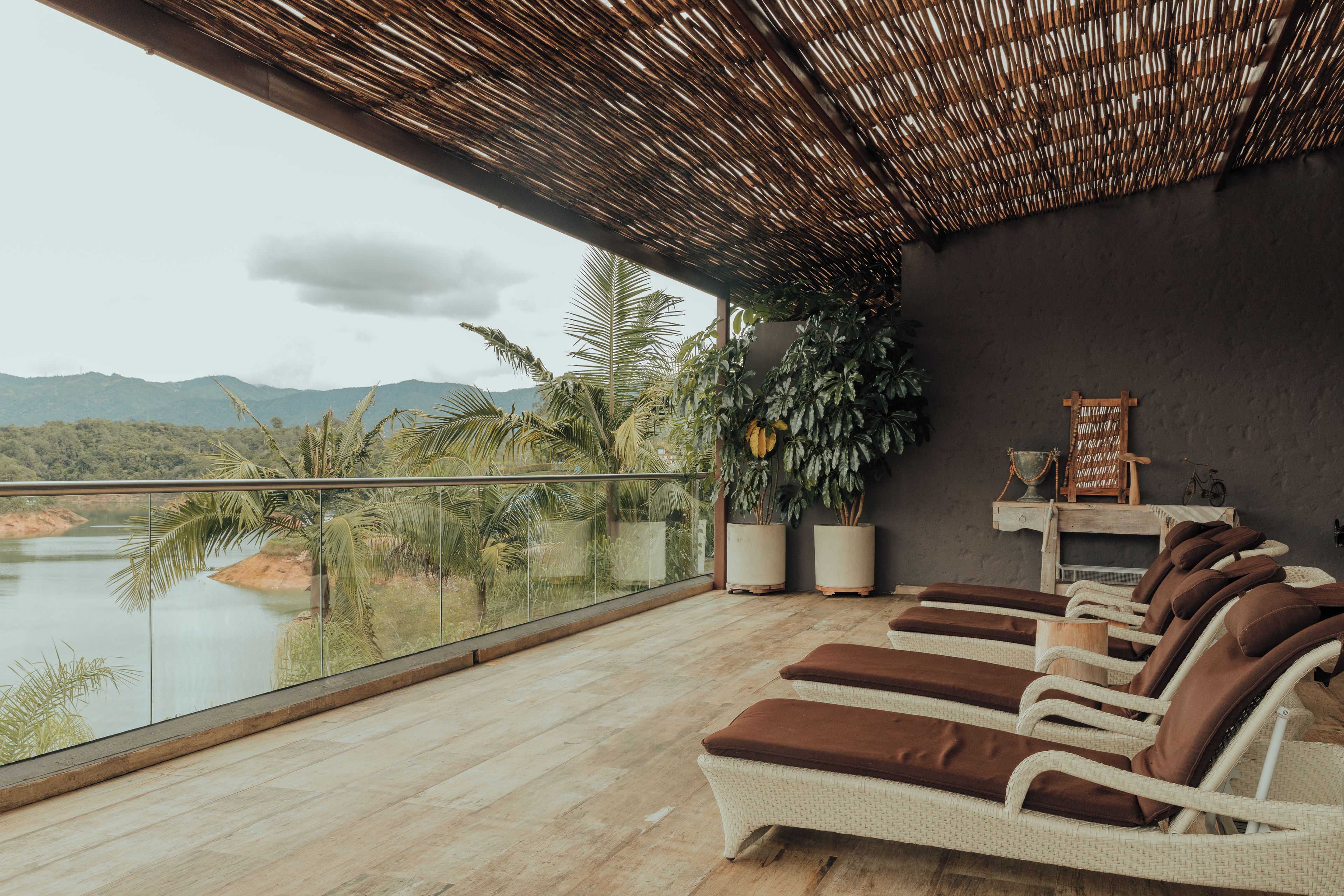 Un balcon avec des fauteuils de jardin en osier et une vue sur un lac et des montagnes.