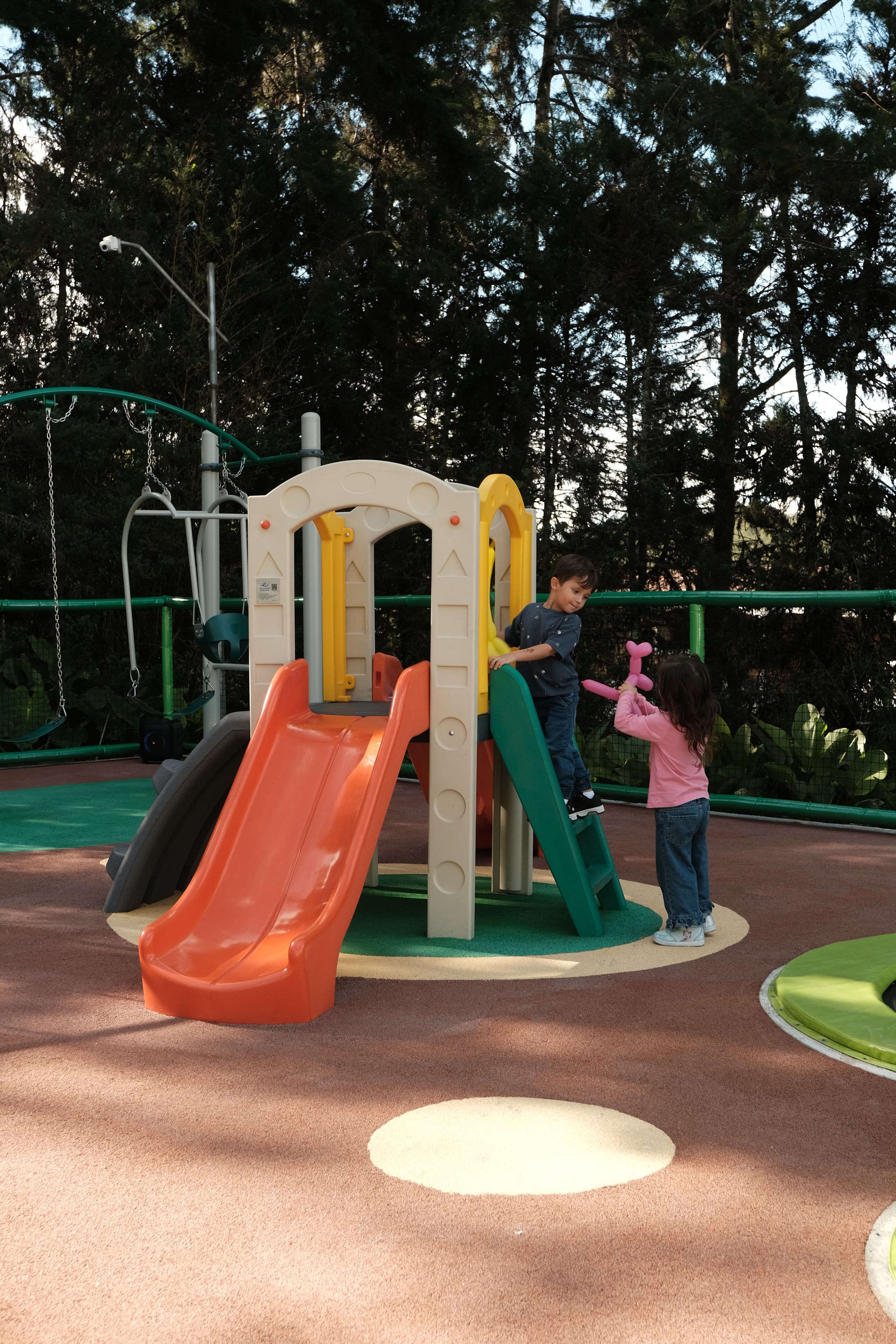 A playground with a slide, climbing structures, and a fenced area.