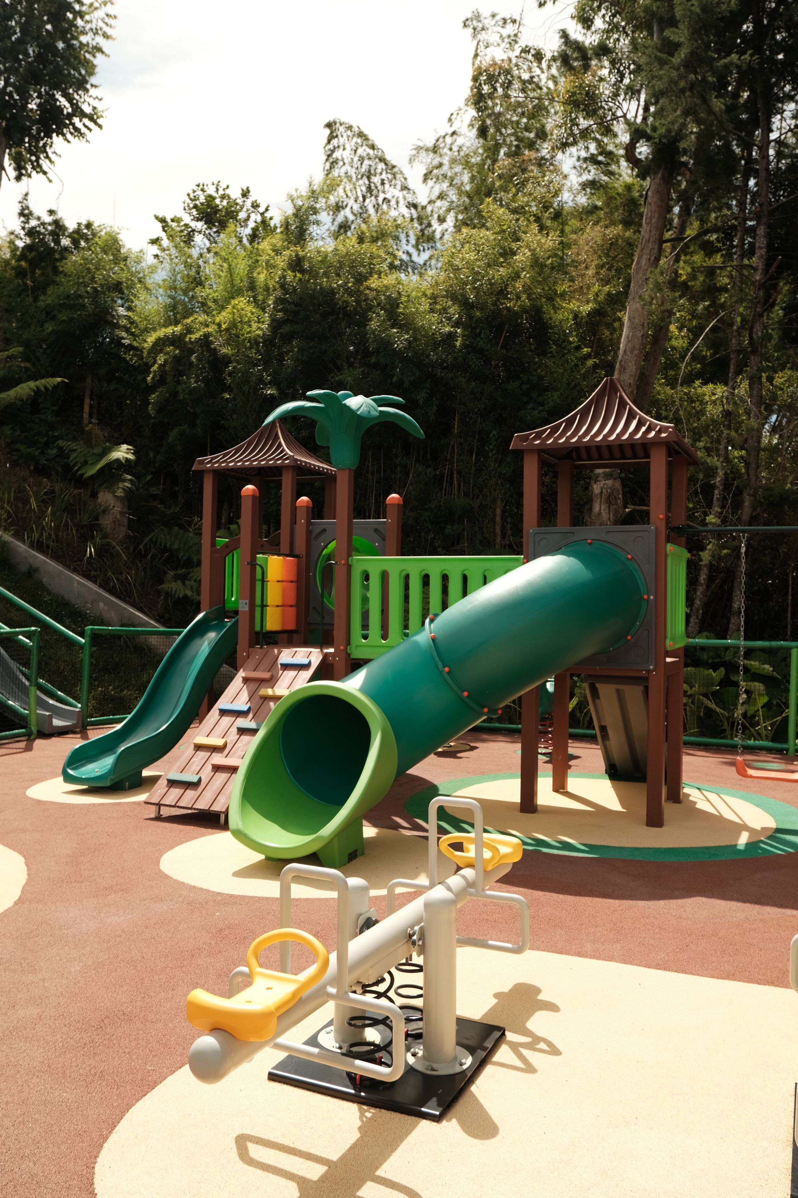 A playground with a slide, climbing structures, and a seesaw.