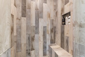 Un baño con diseño de pared de madera y repisas con artículos de tocador.