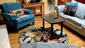 Ein Wohnzimmer mit blauem Sessel, einer Couch, einem Couchtisch und einem gemusterten Teppich.