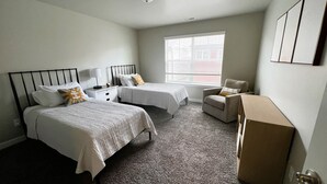 A hotel room with two beds, a chair, a desk, and a window. - It's all about Location! This Downtown Retreat = easy access to the heart of GJ. (Grand Junction)