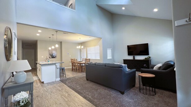 A spacious living area with a grey sofa, a coffee table, and a TV mounted on the wall. - It's all about Location! This Downtown Retreat = easy access to the heart of GJ. (Grand Junction)