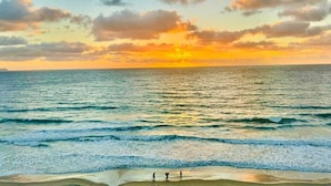 Une plage avec des vagues et un coucher de soleil.