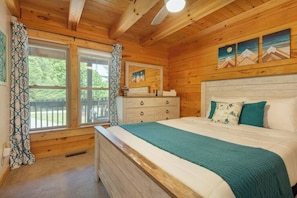 Une chambre dans une cabane en bois, avec un lit, une commode et une fenêtre avec des rideaux.