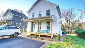 Une maison à deux étages avec un porche abrité, une voiture garée dans l’allée et une pelouse bien entretenue.