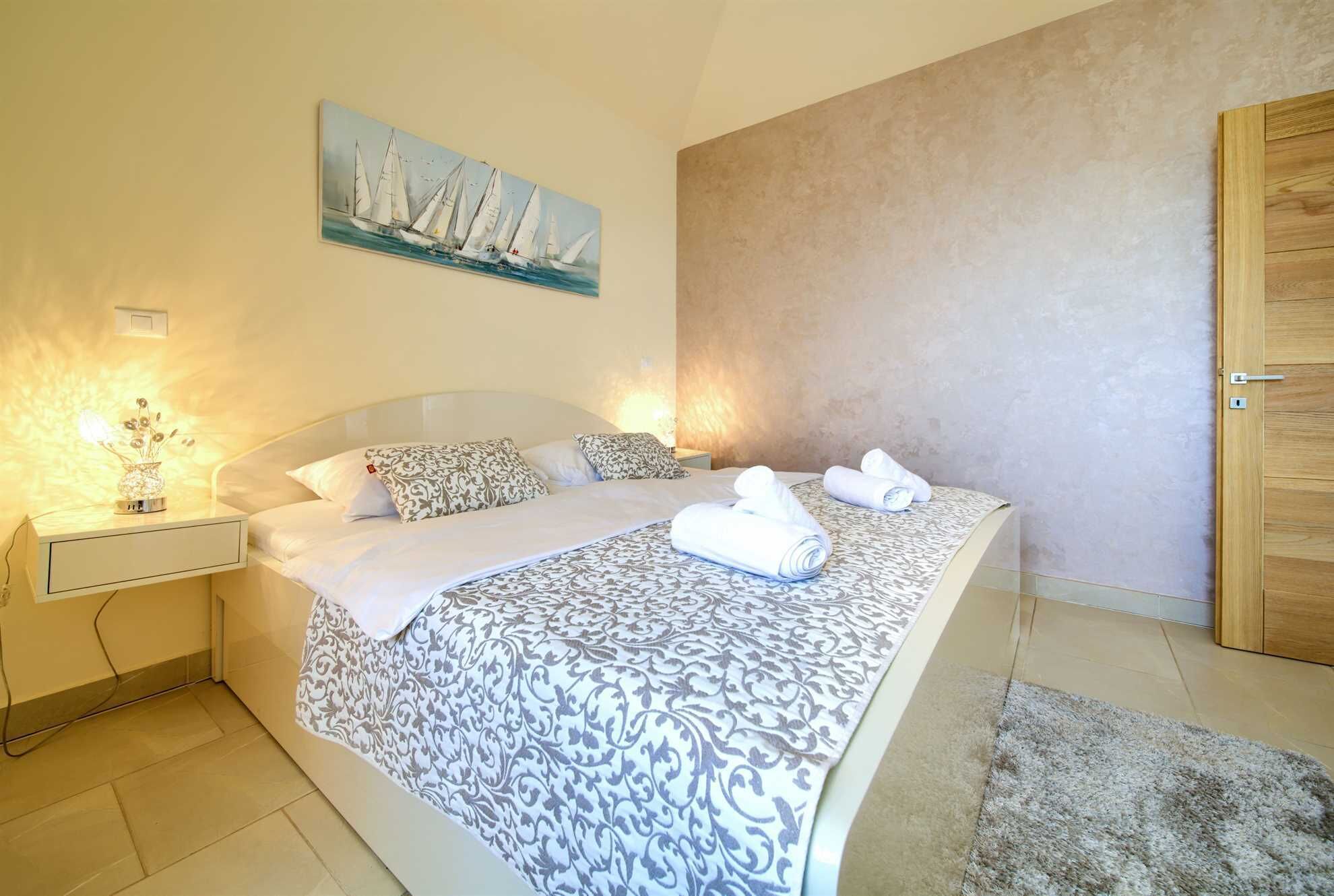 A bedroom with a bed, bedside tables, a painting, and a door.
