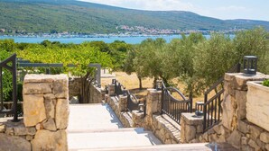 A stone staircase leading to a terrace with a view of a coastal town and mountains. - Apartment ROYAL 1 with pool and jacuzzi (Kornić)