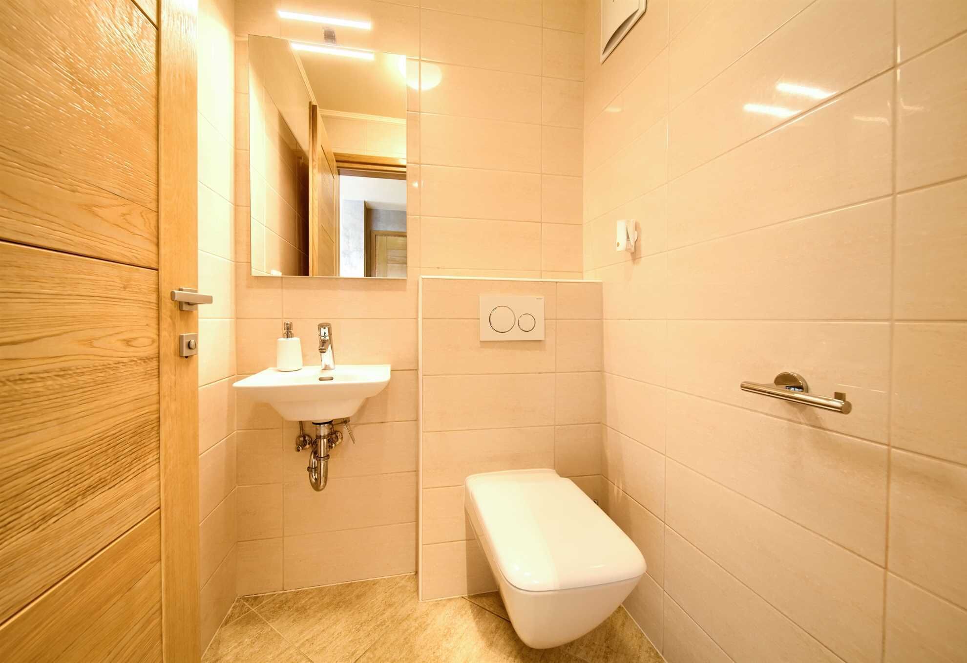 Ein kleines Badezimmer mit einem Holzkosmetikschrank, einem Waschbecken, einer Toilette und einem Spiegel.