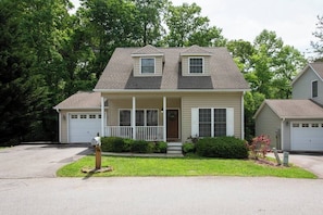 A two-story house with a front porch, a garage, and a well-maintained lawn.