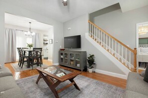 A living room with a wooden coffee table, grey sofa, and a staircase with white railings.