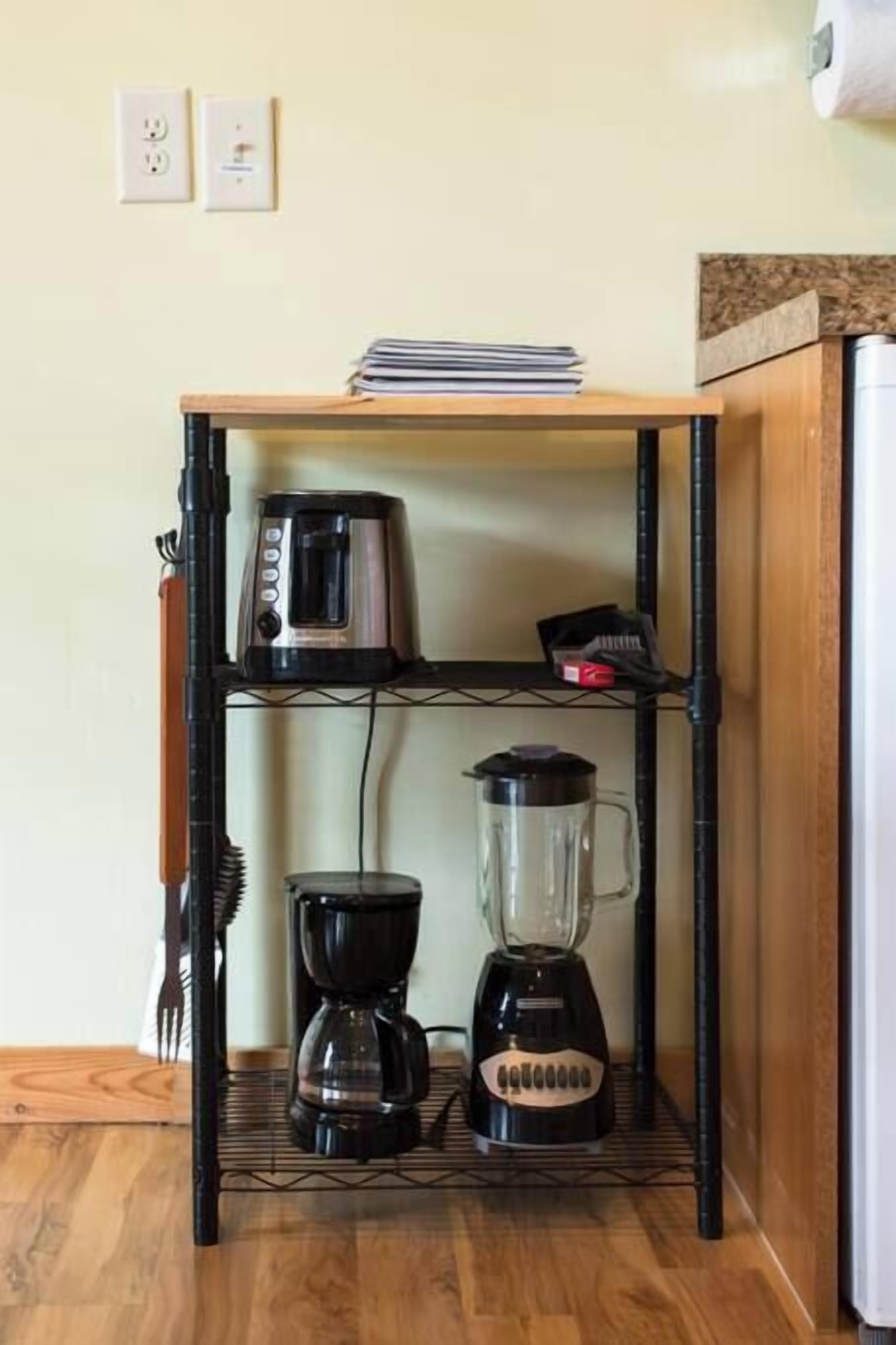 Un coin cuisine équipé d’une machine à café, d’un mixeur et d’un grille-pain, le tout placé sur une étagère.