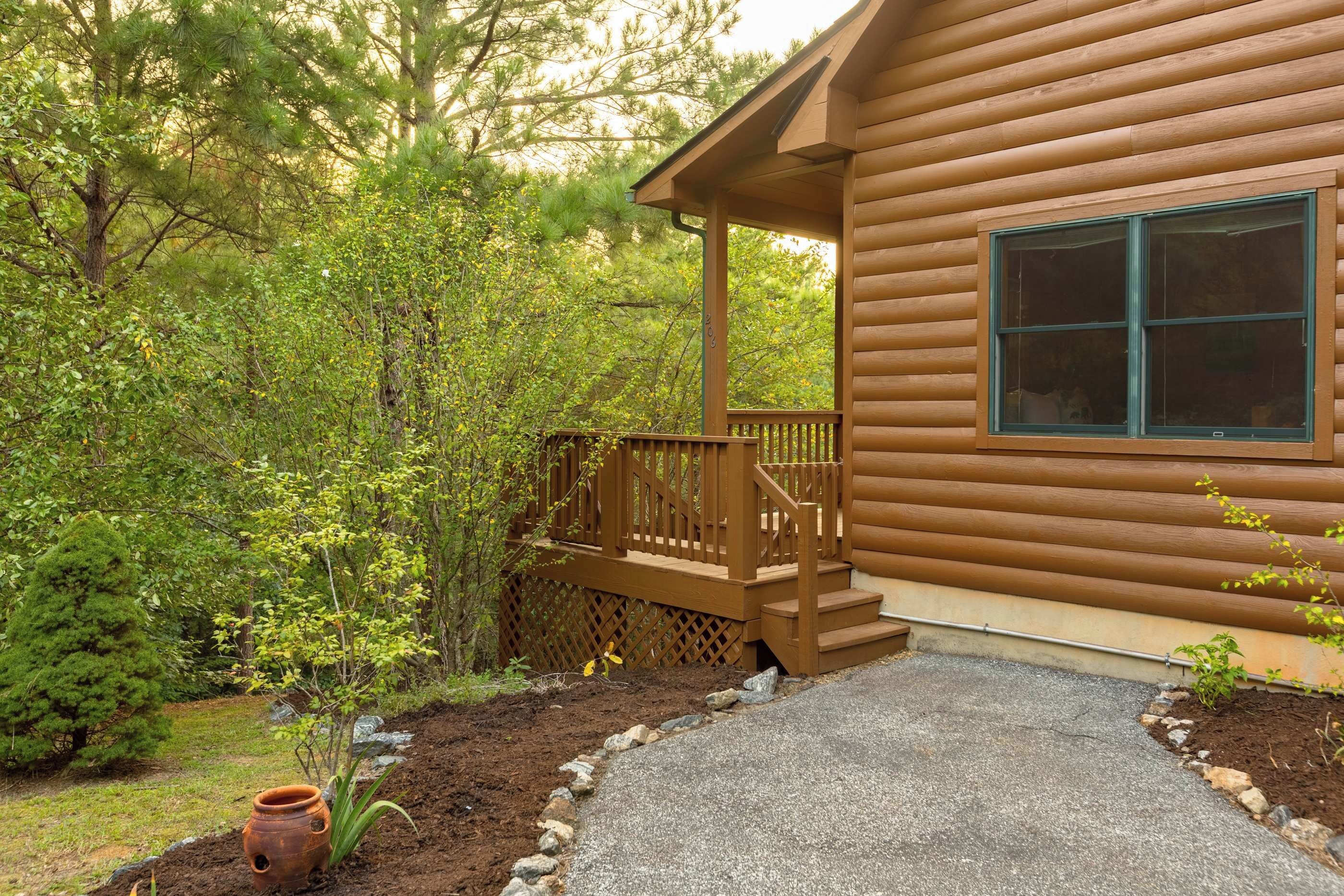 A wooden cabin with a porch, a window, and a stone pathway leading to the entrance.