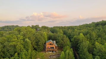 A wooden cabin surrounded by dense forest, with a clear sky above.