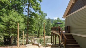 Une maison dotée d’une terrasse en bois, d’un chemin en pierre et offrant une vue sur une zone boisée.