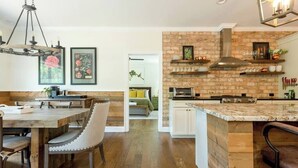 Une cuisine moderne avec un mur d’accent en briques, des meubles de cuisine en bois et un îlot central.