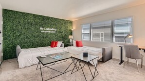 Uma sala de estar moderna com parede verde, um sofá, uma mesa de centro e uma escrivaninha com cadeira.