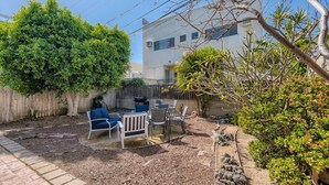 Um quintal com área de varanda, móveis de exterior e diversas plantas.