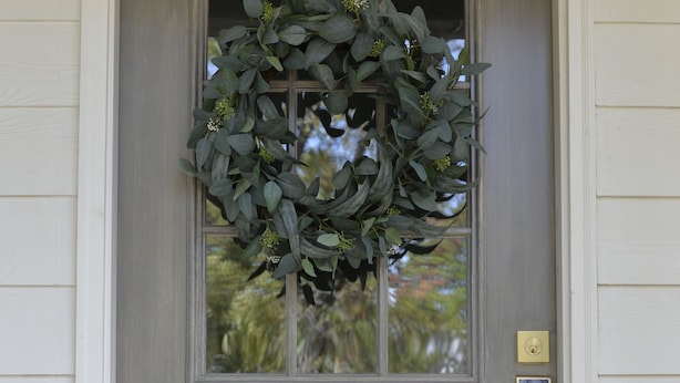 Una puerta delantera gris con un felpudo, una ventana pequeña y un timbre.