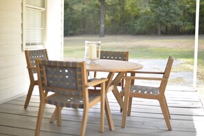 Ein Holztisch mit Stühlen auf einer Veranda, mit einem Kerzenhalter aus Glas.