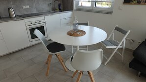 Eine moderne Küche mit weißen Schränken, einem runden Esstisch und vier Stühlen.
