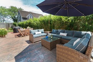 A patio with wicker furniture, a glass coffee table, and a large umbrella.
