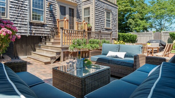 Een terras met tuinmeubilair, een tafel met glazen blad en een trap naar een houten terras.