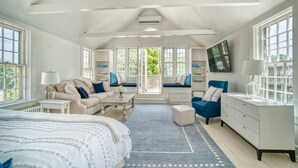 Een ruime slaapkamer met een groot bed, een bank, een stoel, een dressoir en een televisie.