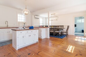 A spacious kitchen with white cabinetry, a wooden island, and a dining area with a wooden table and chairs.