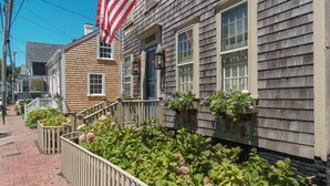 Een gebouw met twee verdiepingen, een houten gevel, een veranda met een leuning en een vlaggenmast met een Amerikaanse vlag.