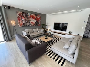 Una sala de estar moderna con un sofá gris, un tapete a rayas negras y blancas y un cuadro abstracto grande en la pared.