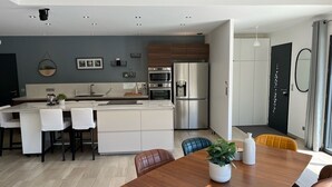 A modern kitchen with stainless steel appliances, a central island, and a dining area with a wooden table and chairs.
