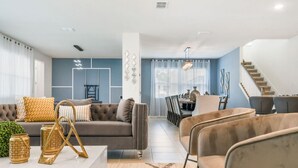 Un salon moderne comprenant un canapé, des fauteuils et un coin repas avec une table et des chaises.