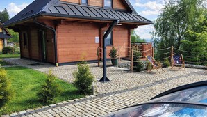 A wooden cabin with a swimming pool, surrounded by a cobblestone path and greenery.