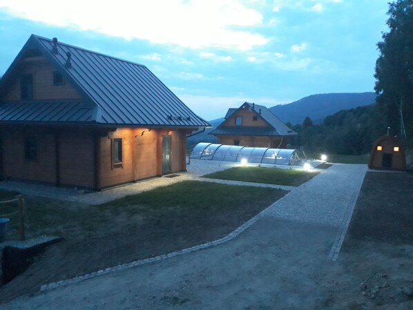 A rustic building with a sloped roof and a well-lit entrance. - 2 - bedroom mountain chalet with sauna and hot tub (Jugów)