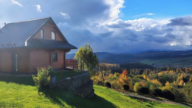 A rustic house with a metal roof, a stone wall, and a wooden deck.
