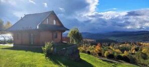 A rustic house with a metal roof, a stone wall, and a wooden deck. - 2 - bedroom mountain chalet with sauna and hot tub (Jugów)