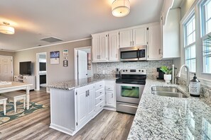 Enjoy cooking in this well-lit kitchen with white cabinetry, granite countertops, and stainless steel appliances.