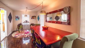 A dining area with a long wooden table, colorful chairs, a mirror, and artwork on the walls. - Horsefeathers 🐾 pet friendly funky comfort (Amarillo)