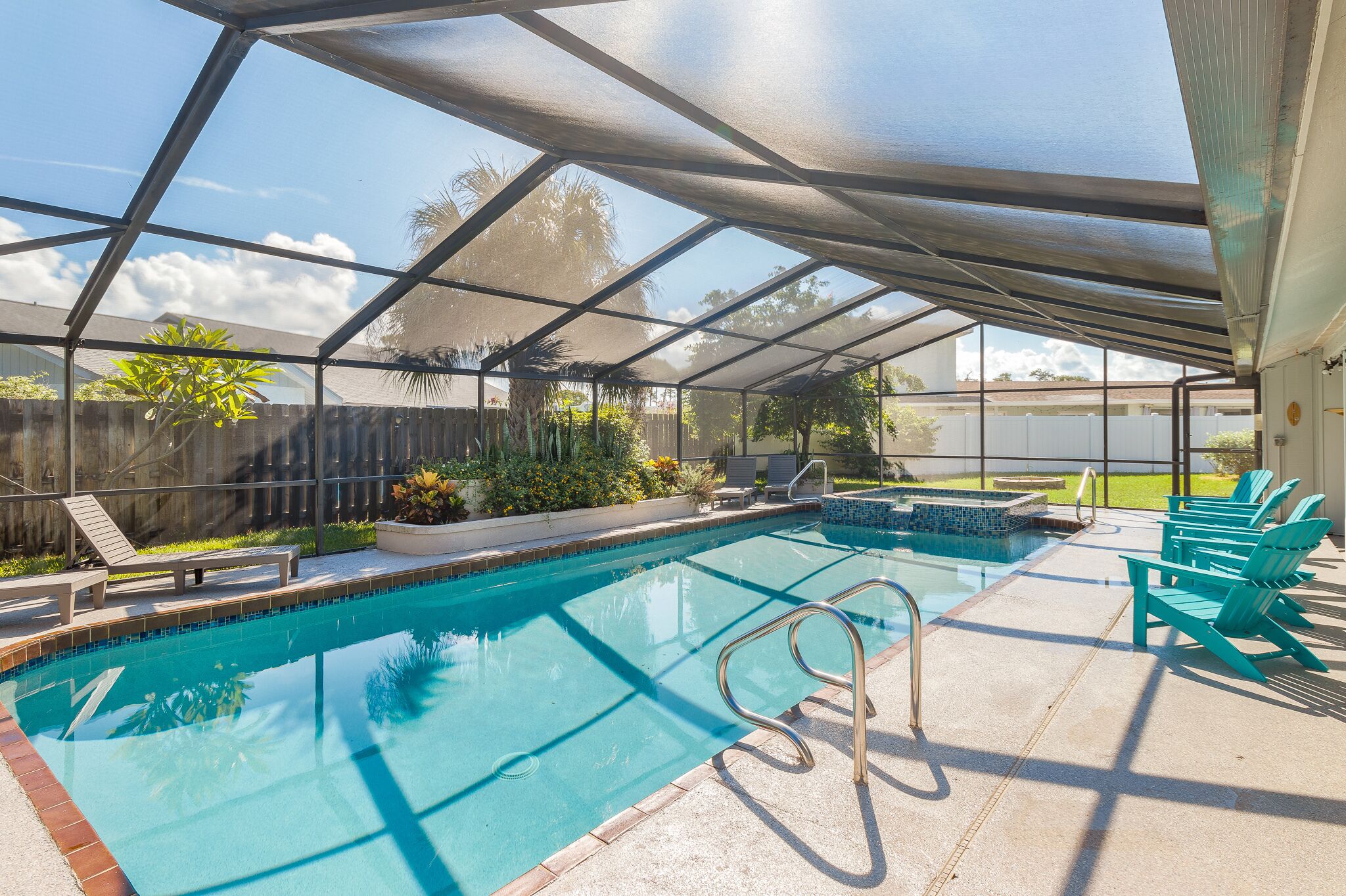 Une piscine intérieure protégée par une structure en verre, dotée de chaises longues et d’un jacuzzi.