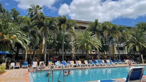Un área de piscina con sillas de descanso y palmeras.