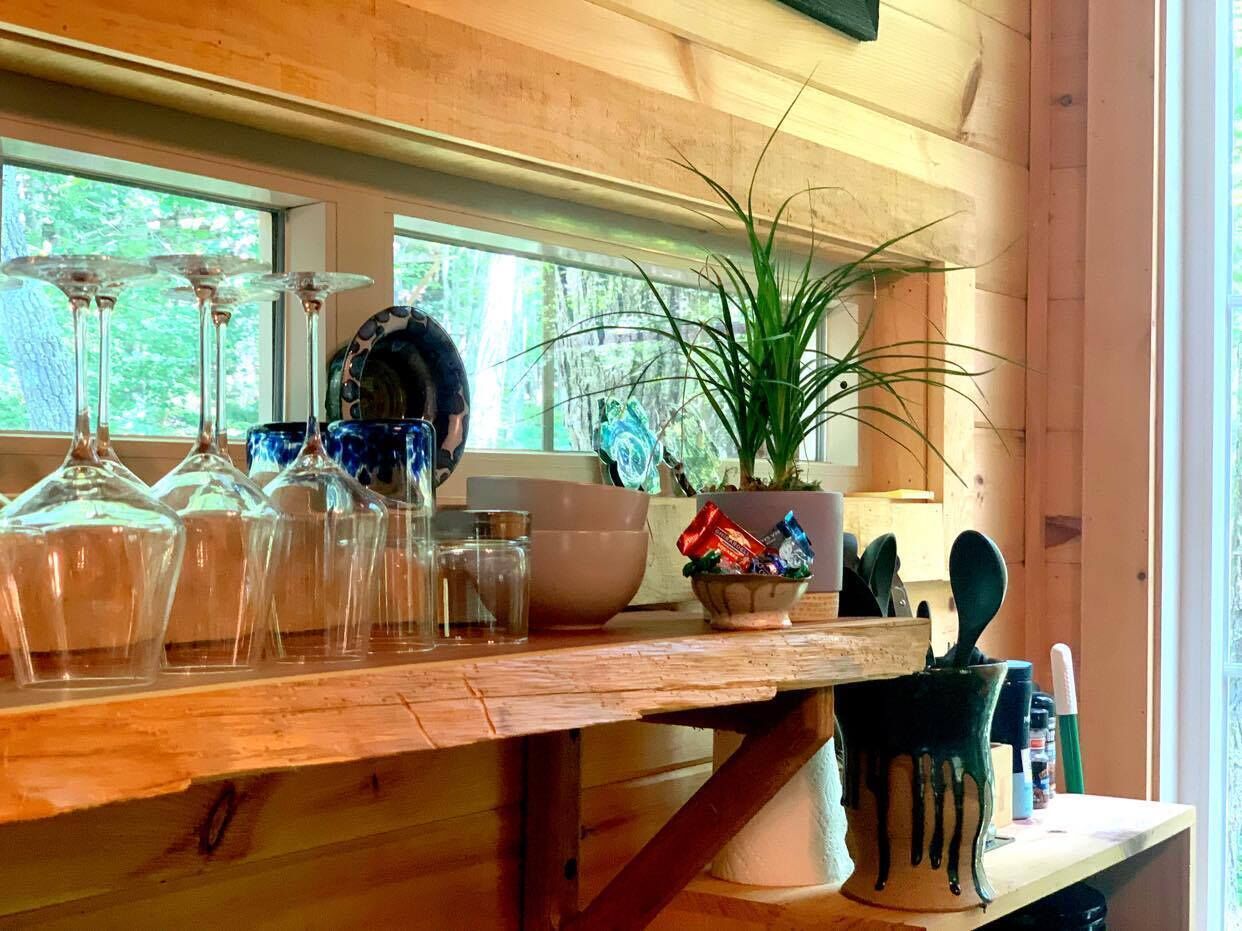 A wooden kitchen counter with glassware, a bowl, a potted plant, and kitchen utensils.
