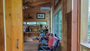 A wooden cabin interior with a dining area, a kitchen, and a seating area with a view of the outdoors. - Dreamy Treehouse Getaway ~Dog Friendly~Disc Golf (Copperhill)