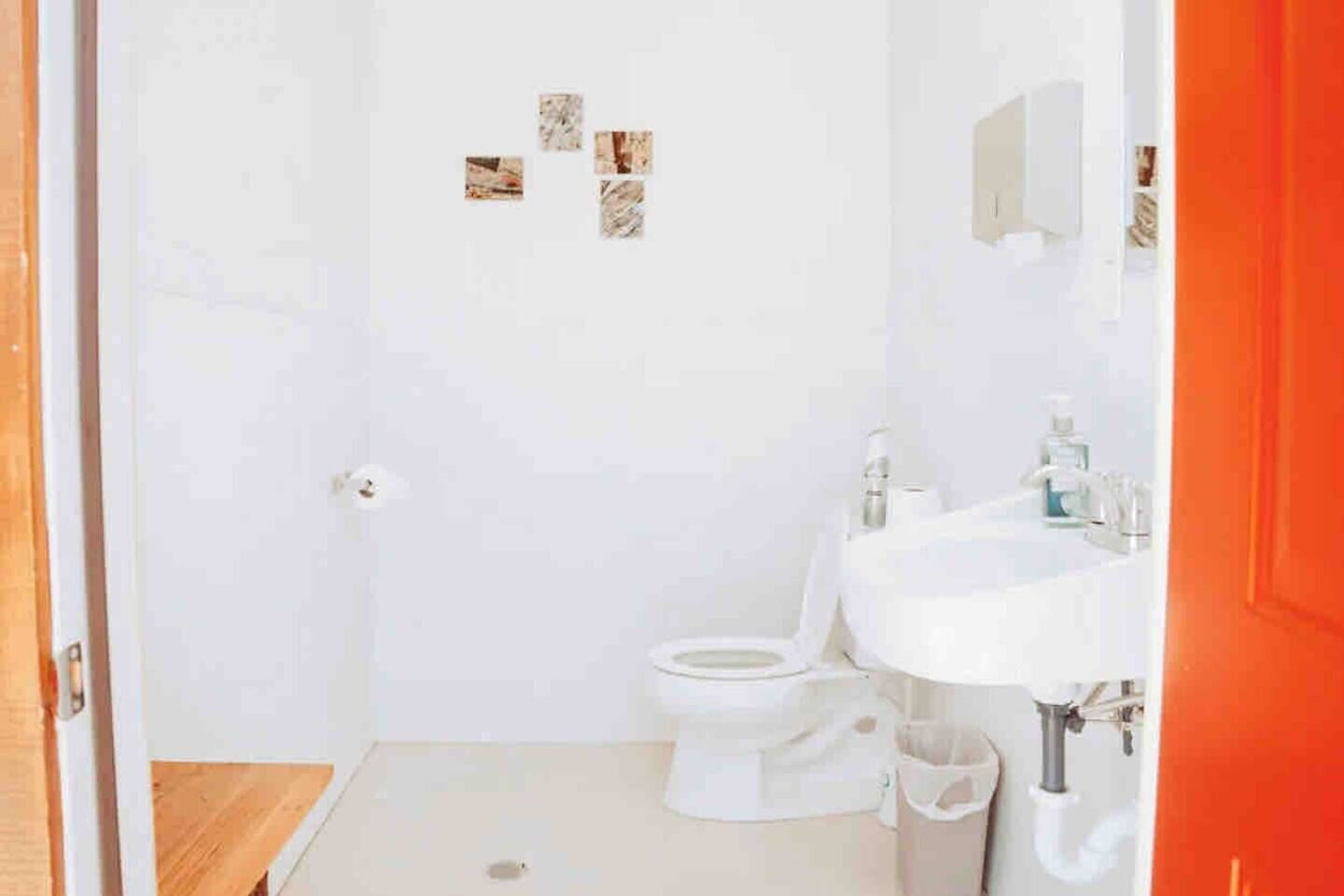 Une petite salle de bain blanche, avec des toilettes, un lavabo et un miroir au-dessus du lavabo.
