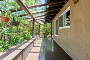 A wooden deck with a pergola, surrounded by lush greenery. - Stupa EcoVila (Imbituba)