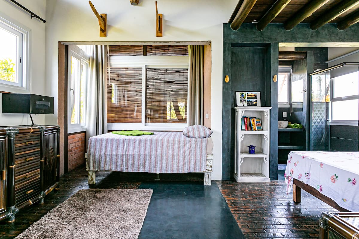 A bedroom with a bed, a bookshelf, and a window with blinds.