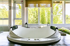 A modern bathroom with a freestanding bathtub, large windows, and a view of greenery outside. - Stupa EcoVila (Imbituba)