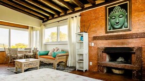 Una habitación acogedora con una cama, un sofá, una chimenea y una estatua de Buda.